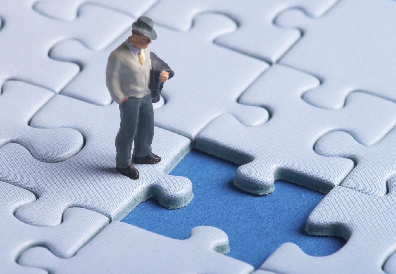 Mann betrachtet nachdenklich fehlendes Puzzlestück; symbolisiert, wie Therapie hilft, fehlende Lebenspuzzleteile zu finden und einzufügen